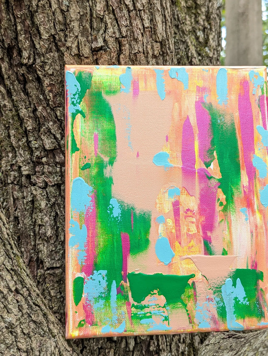 Colorful abstract painting leaning against a tree