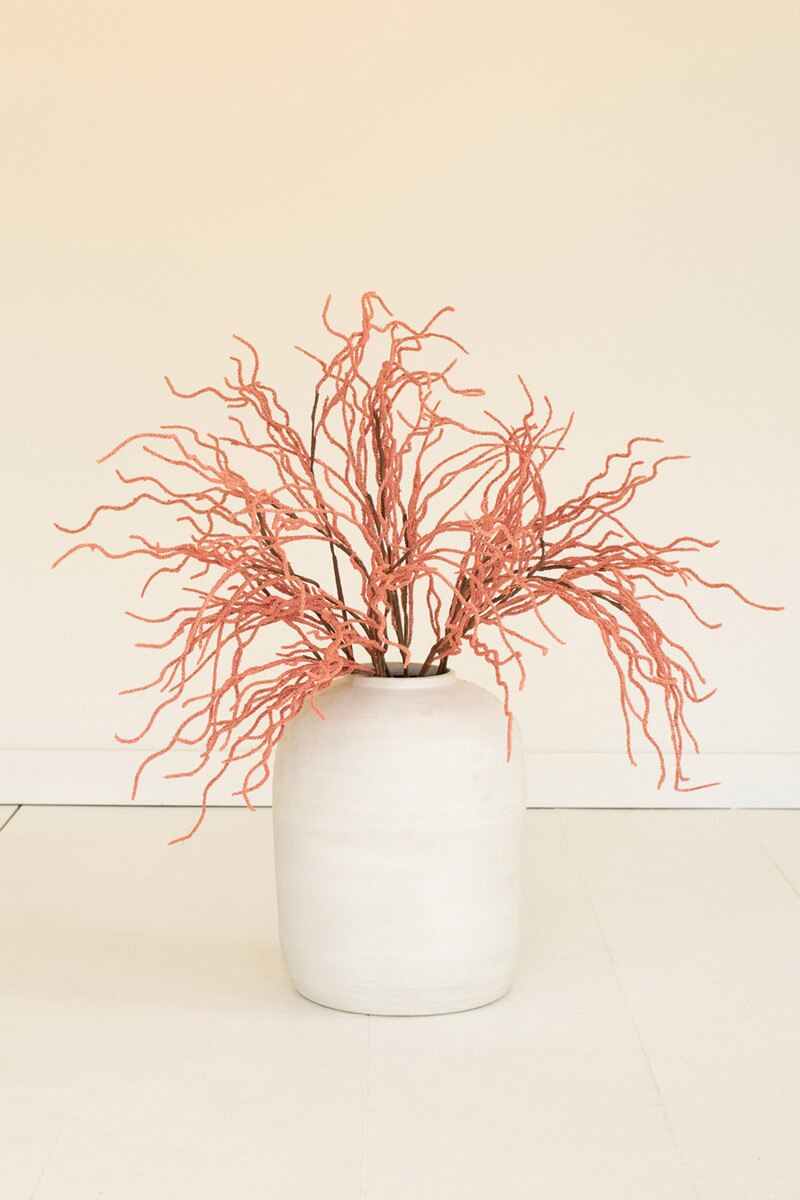 White vase with pink dried branches on a beige background