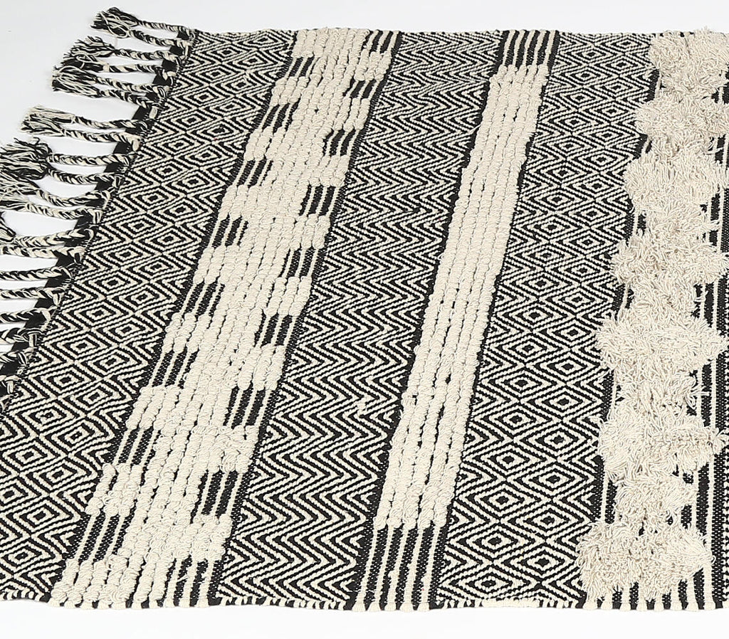 geometric tufted cotton rug with tassels - shallow angled view