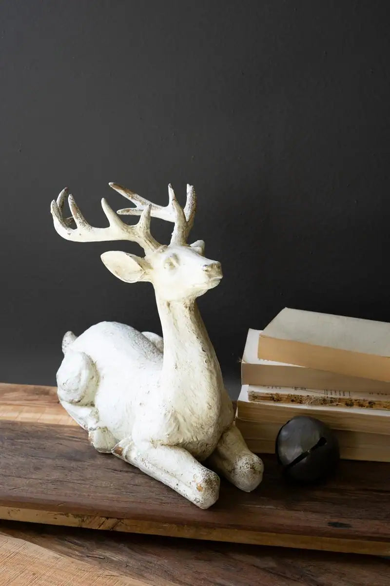 faux concrete deer resting next to short stack of books