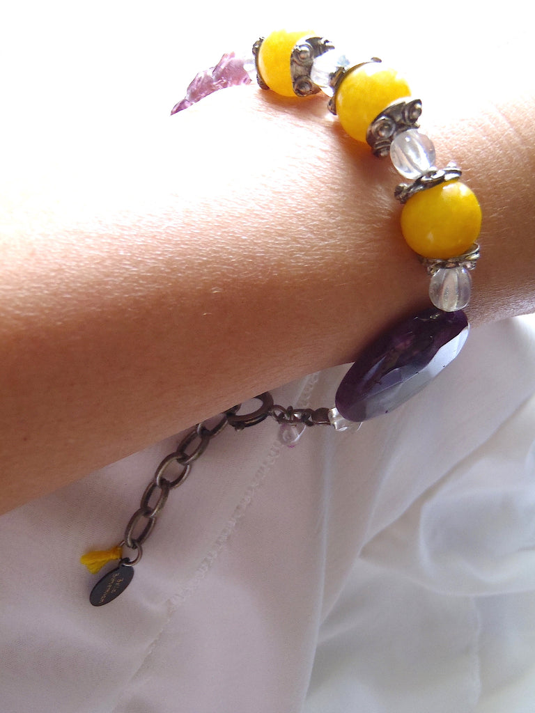 braclet with combination of yellow round jade and purple glass bead shown on a lady's wrist