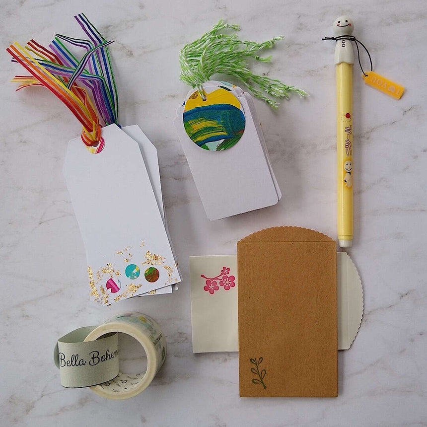 confetti and gold foil gift cards, white gift tags, mini envelopes, Japanese washi tape, Japanese sunny doll black pen laid out on a table