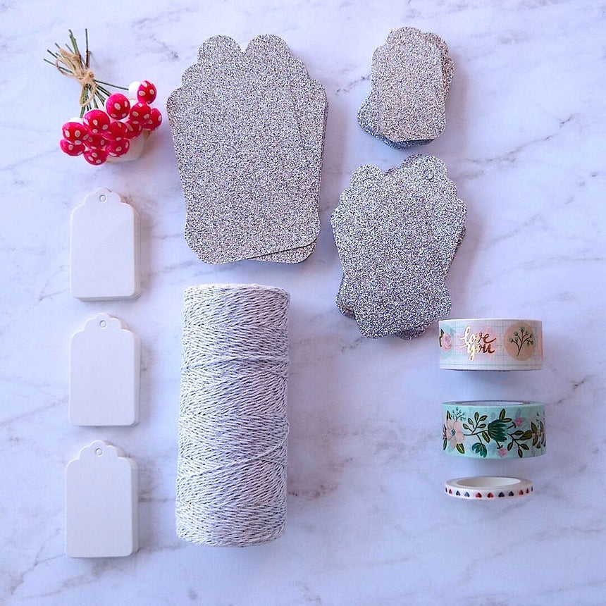 silver luxe glitter gift cards, white hang tags, German cotton spun mushrooms, metallic glitter bakers twine differently laid out flat