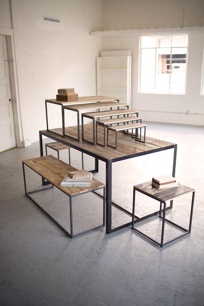 A nested display set consisting of recycled wood look with metal frames, including a table and a bench, intended for retail use.