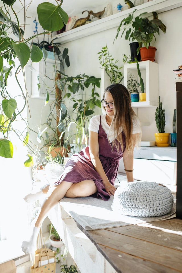 Young woman content at home among shabby decor and plants