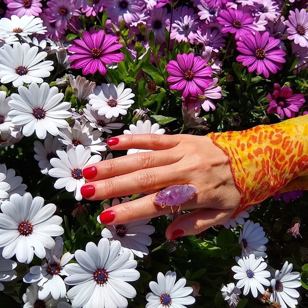 amethyst cocktail ring worn on woman's hand with flower background