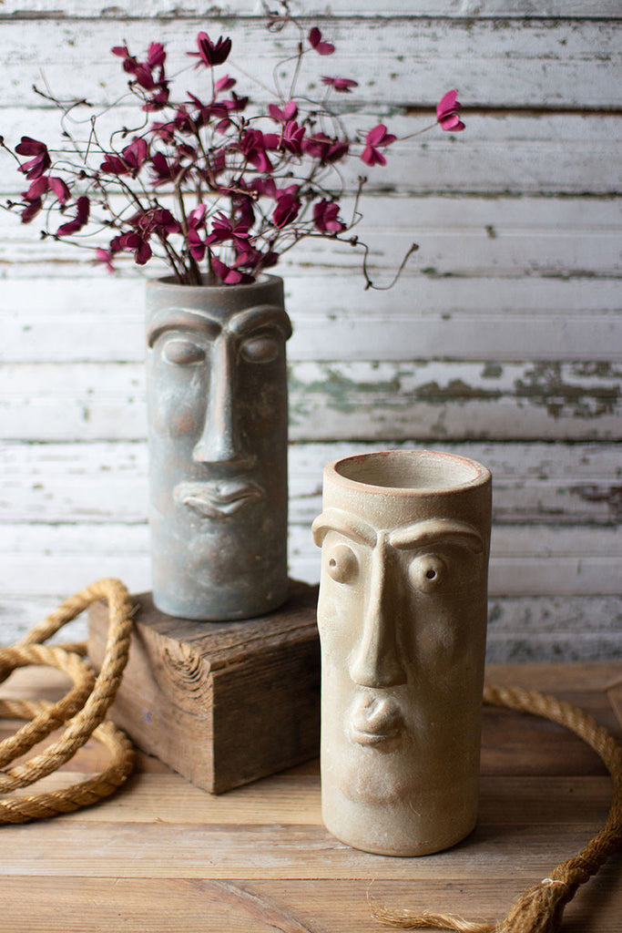clay face vases one with fuchsia flowers