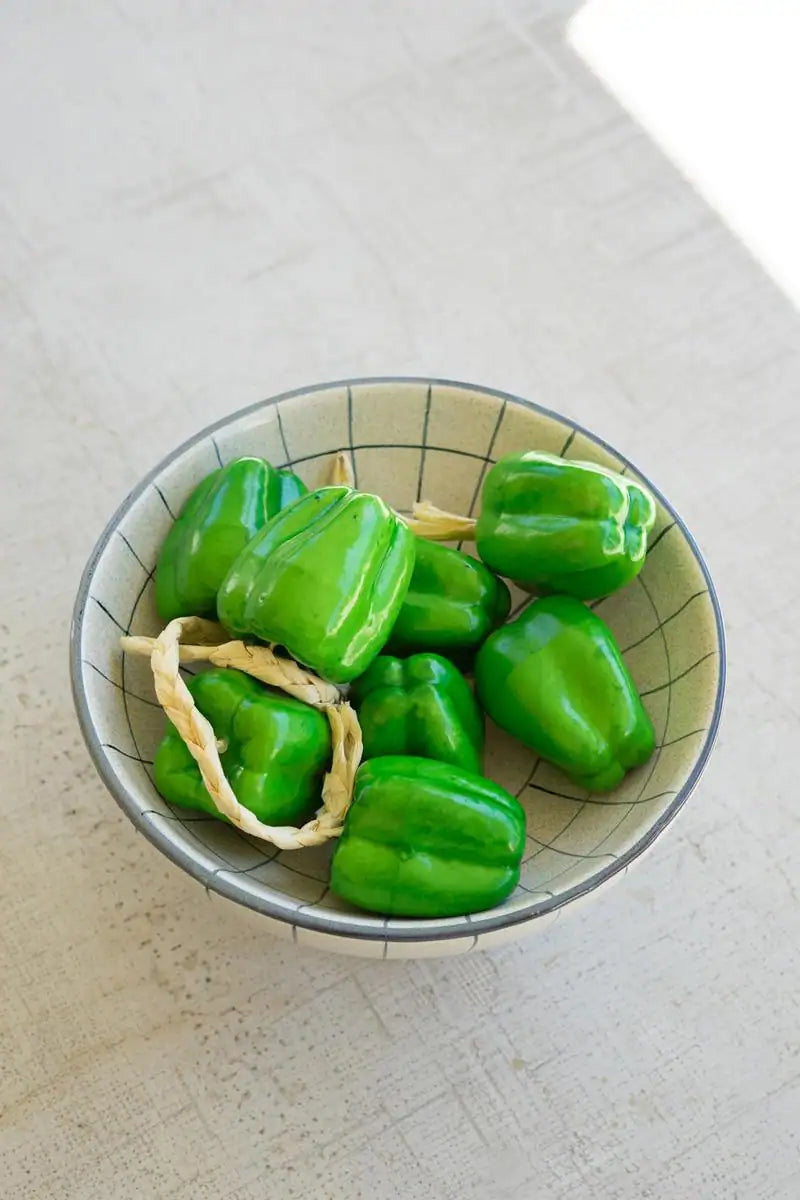 string of green faux bell peppers - shown in a bowl