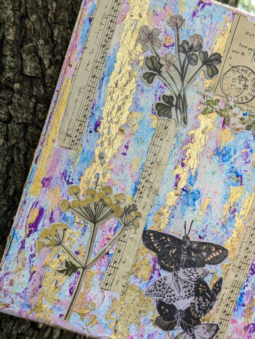 Angled perspective of decorative mixed media canvas collage with floral, music and butterfly design