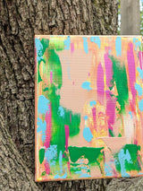 Colorful abstract painting leaning against a tree