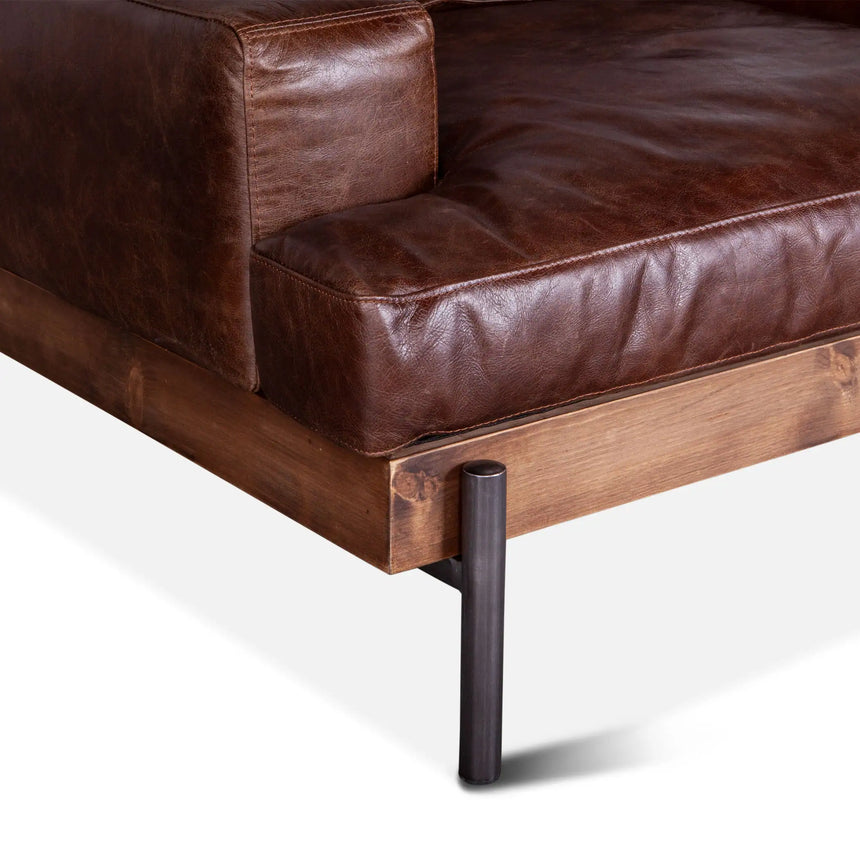 rustic brown leather armchair with wood frame and metal legs - close-up of one foot