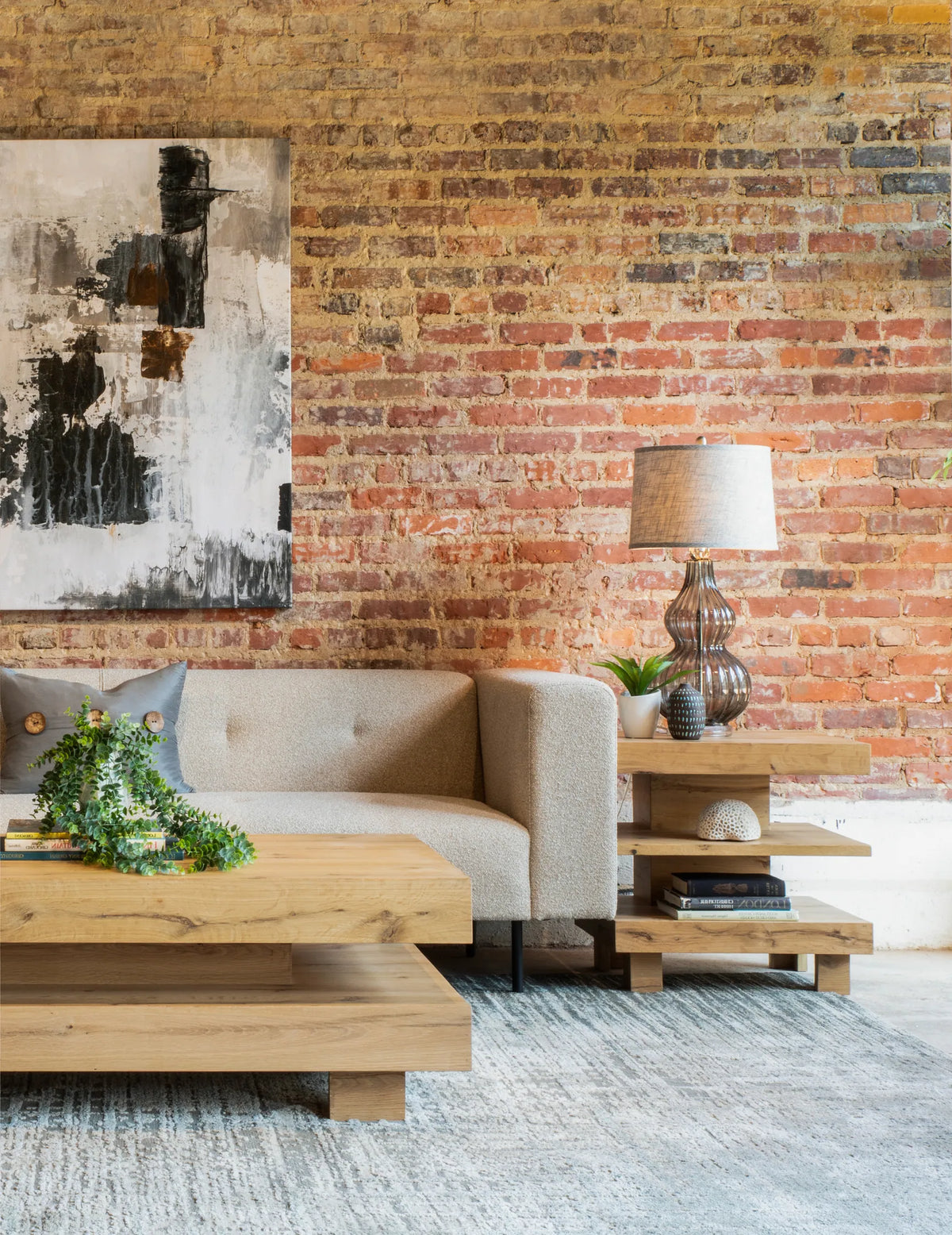 55in Alpine Coffee Table in Distressed Oak - shown in room with brick wall and light color sofa - portrait photo