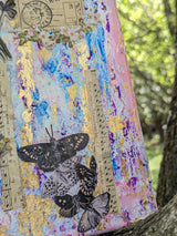 Bottom right close-up of original mixed media canvas collage held by tree trunk background