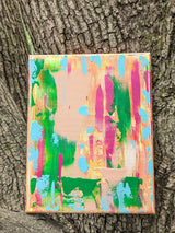 Colorful abstract painting against a tree trunk background
