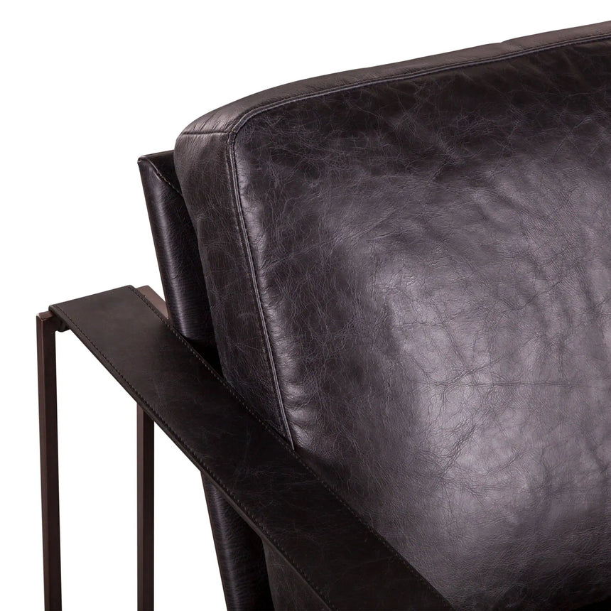 black leather chair with dark brown metal frame and leather strap arm rests - close-up of back cusion