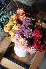 bundles of mustard colored faux zinnias shown with multiple other colors