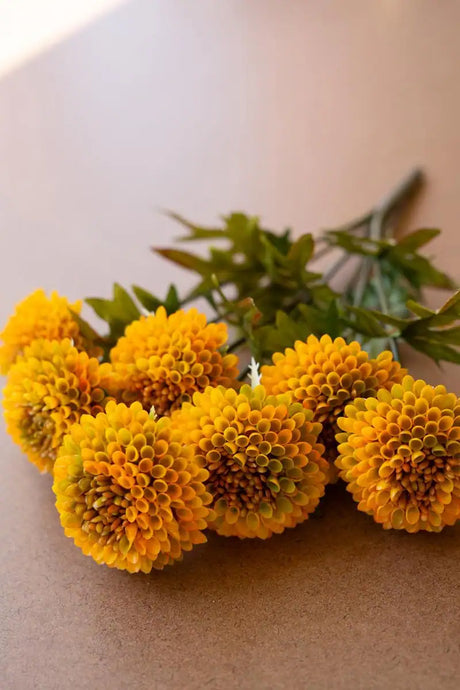 bundles of mustard colored faux zinnias - close-up