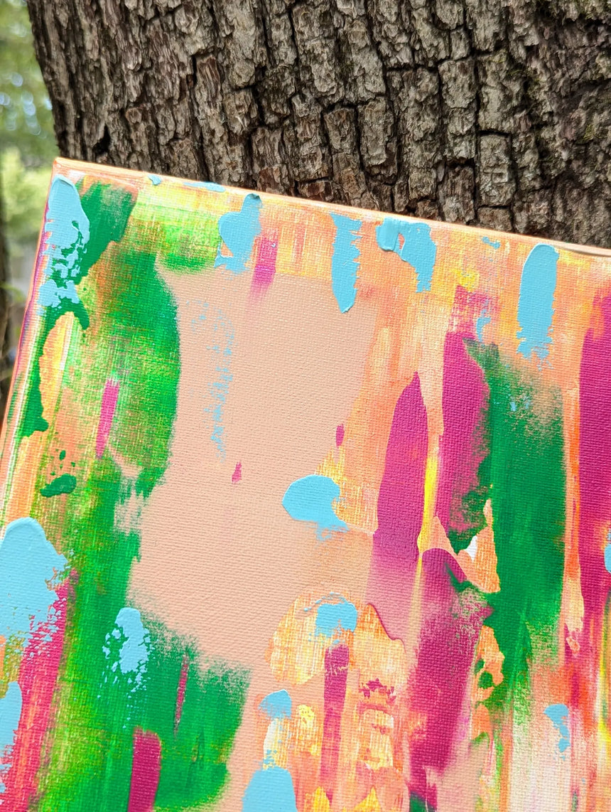 Colorful abstract painting leaning against a tree with focus on upper left corner