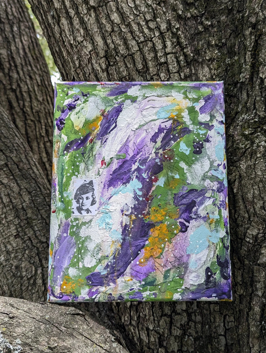 Original colorful abstract painting propped up against a tree trunk background for contrast