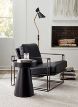 Studio photo of leather armchair with side table and floor lamp and some books on the floor rug