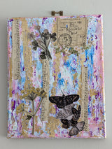 Original decorative mixed media canvas collage with floral, music and butterfly design hung on white wall background