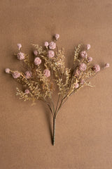 Artificial flower arrangement with pink and gold elements on a brown background