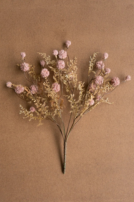 Artificial flower arrangement with pink and gold elements on a brown background