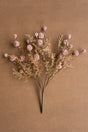 Artificial flower arrangement with pink and gold elements on a brown background