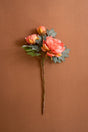 Artificial flower arrangement of long stem coral color peonies against a brown background