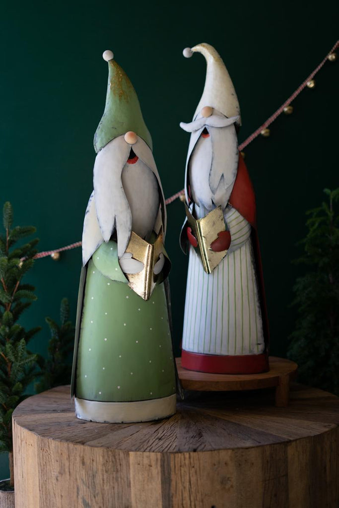 set of 2 caroling santas - one with green cloak, another with a white cloak, blue stripes and a red cape standing on wood block