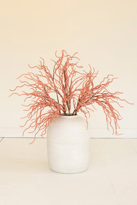White vase with pink dried branches on a beige background