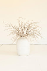 White vase with dried branches on a light beige background
