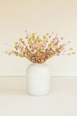 White vase with pink and yellow flowers on a light beige background