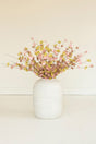 White vase with pink and yellow flowers on a light beige background