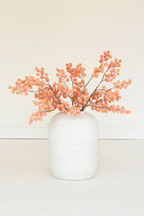 White vase with coral-colored branches on a light background