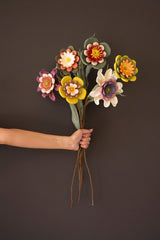Hand holding a bouquet of colorful foam flowers against a dark background