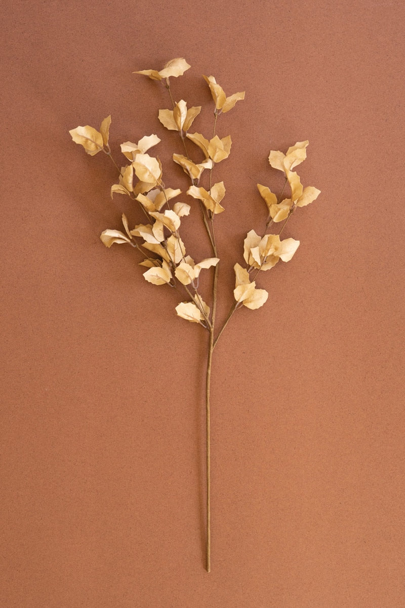 Artificial gold flower branch on a brown background