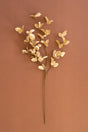 Artificial gold flower branch on a brown background