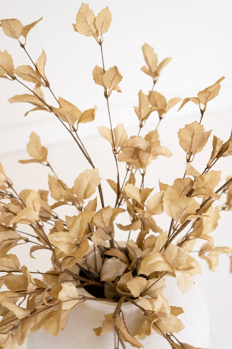 Artificial gold leaves in a pot on a white background