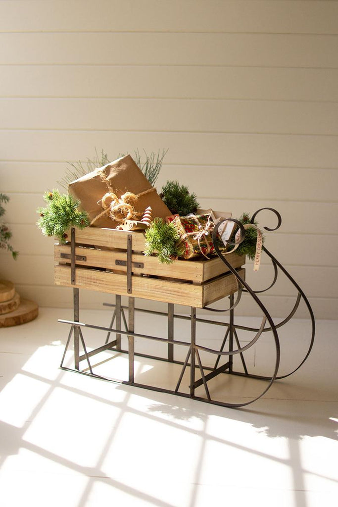 metal framed wood sleigh with gifts and evergreen twigs sitting in it
