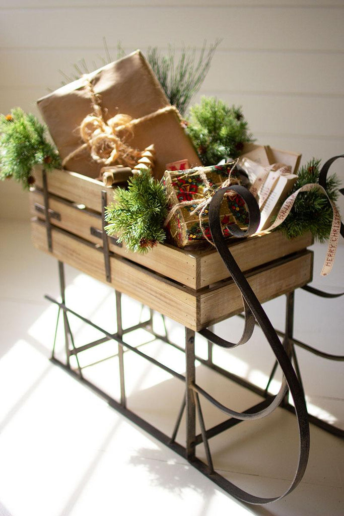 metal framed wood sleigh with gifts and evergreen twigs sitting in it - angled close-up view