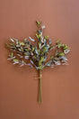 A dried artificial eucalyptus branch bundle with muted green, gray, and soft pink leaves tied with natural twine, displayed against a solid terracotta brown background.
