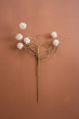 A faux dried floral wall sculpture featuring five white starburst flowers on branching tan and brown stems, displayed against a solid terracotta background.