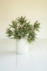 Artificial green potted plant on a white floor with a white wall background