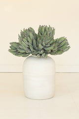 Green faux succulent plant in a white vase on a beige background