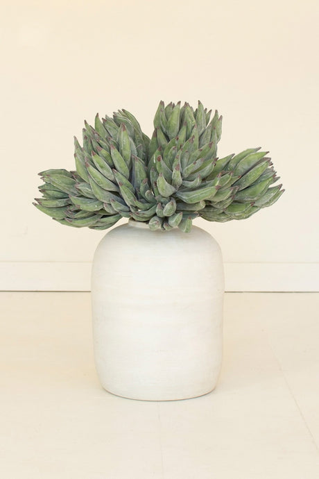 Green faux succulent plant in a white vase on a beige background