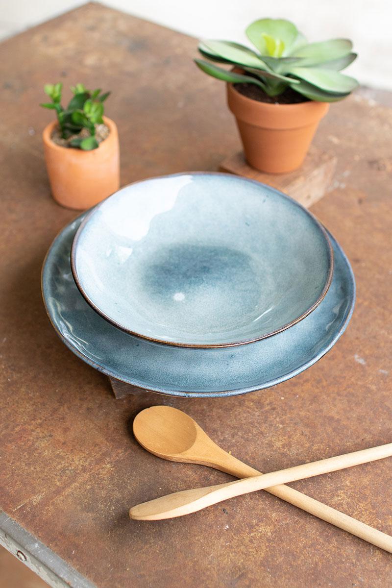 ceramic bowl on top of plate in faded blue color on table - angled view