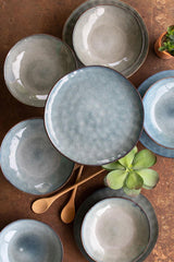 ceramic bowl on top of plate in faded blue color on table - top down view