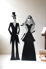 Skeleton bride and groom figures on a white surface with a neutral background