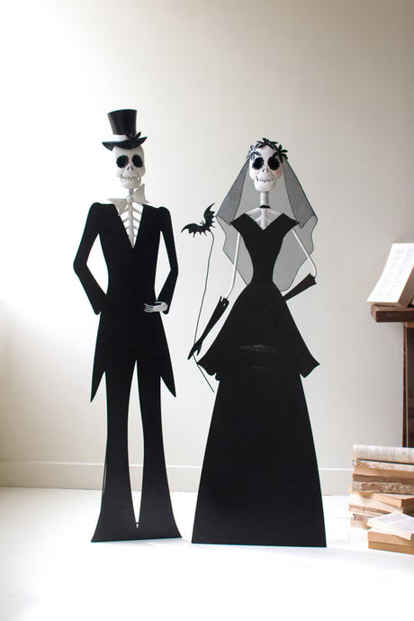 Skeleton bride and groom figures on a white surface with a neutral background